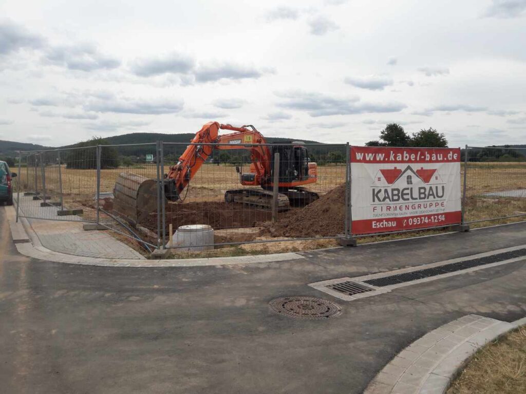 Bagger führt Erdarbeiten an der Baugrube neben der Straße aus.