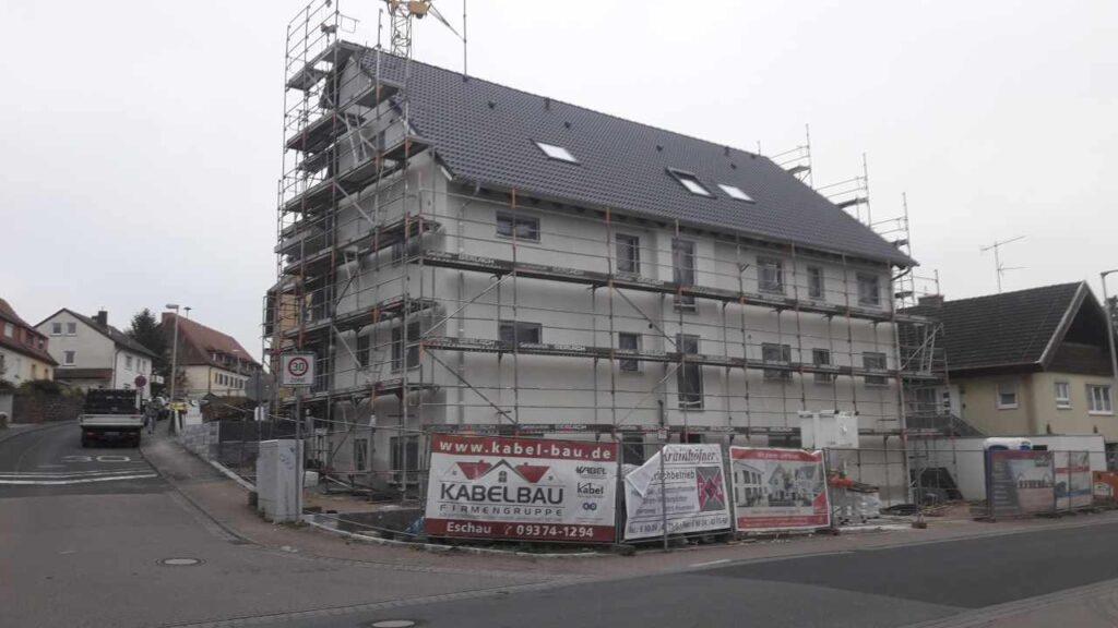 Gebäude vollständig eingerüstet und mit Folie eingehaust.