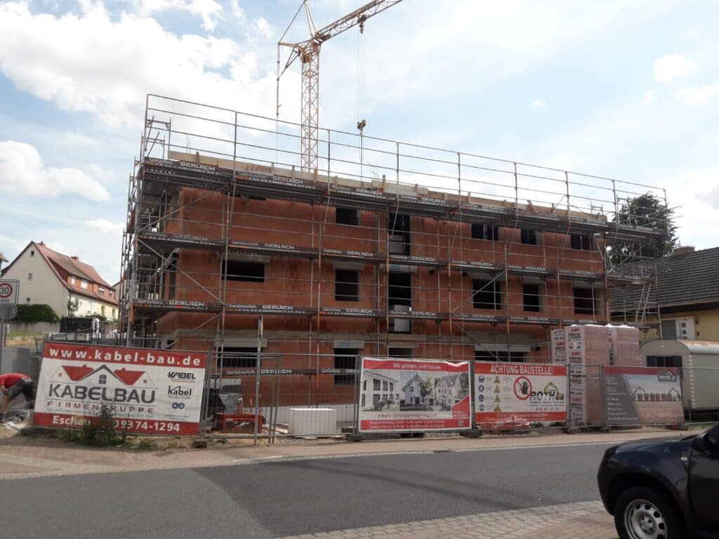 Nachbargebäude im Ziegelrohbau, Gerüst und Kran vorhanden.