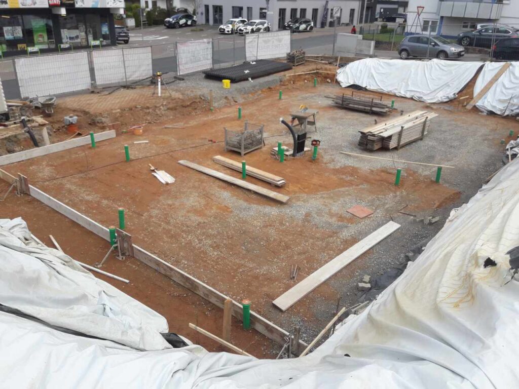 Vorbereitetes Fundamentfeld mit Sauberkeitsschicht, Markierungen und aufstehenden Leitungen.