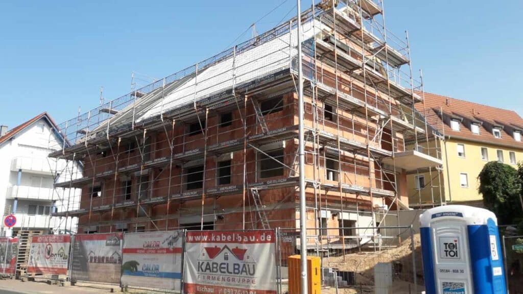 Hauptfassade mit Gerüst; Dachdeckung und Ausbau laufen.